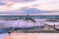 Boat jetty hit by strong waves at sunset.