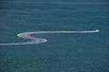 Boat leaving a white 'S' shaped trail on the sea water surface