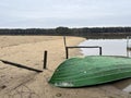 A boat lying upside down on the beach of a small lake in early spring after the snow and ice have gone Royalty Free Stock Photo