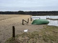 A boat lying upside down on the beach of a small lake in early spring after the snow and ice have gone Royalty Free Stock Photo