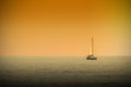 A boat navigating a tranquile sea at sunset time. Dark orange atmosphere.