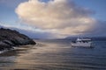 Boat near a desertic islandÃÂ´s shore with sea birds and a cloud with sunlight in Ushuaia, Argentina Royalty Free Stock Photo