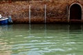 Boat next a ancient brick wall with doors on a canal in Venice, Italy Royalty Free Stock Photo