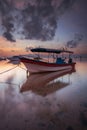 Boat in the ocean. Sunrise view. Low tide. Sunlight on horizon line. Cloudy sky. Water reflection. Soft focus. Slow shutter speed Royalty Free Stock Photo