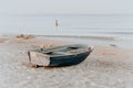 Boat with a paddle on a sandy beach by the sea. Close-up, at dawn. A woman in the sea and a seagull in the background Royalty Free Stock Photo
