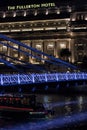 Boat passes under a bridge in front of Fullerton hotel in Singapore at night Royalty Free Stock Photo