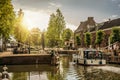 Boat passing by a tree-lined narrow canal in the sunrise at Weesp.