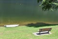 Boat and bench on the grassy shore of Lake Piazze, Trentino, Italy. Royalty Free Stock Photo