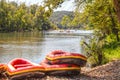 Boat rafts piled on river bank and boats full of rafters and swimmers floating further downstream on the river surrounded by trees Royalty Free Stock Photo