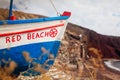 Boat with Red beach writing on Santorini island, Greece on seashore at summer. Close up