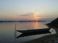 Boat resting on river Bahuda with sunset in the background.