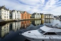 Boat on the river surrounded by colorful buildings under a cloudy sky in Alesund in Norway Royalty Free Stock Photo