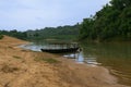 A boat sailed on a bank of a river surrounded by green trees