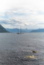 Boat sailing in open sea with big mountains, fjords in the background. Boat setting sail in with big mountains Royalty Free Stock Photo