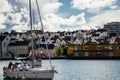 Boat sailing on the sea in the foreground with picturesque houses in the background in Stavanger marina port