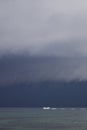 Boat sailing in the upcomming storm. Sailboat in bad weather sail at opened sea. Sailing yacht under heavy cloud sky. Royalty Free Stock Photo