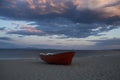 Boat on sand beach on cloudy evening sky. Fishing boat at sea shore after sunset. Summer vacation on sea. Fishing and Royalty Free Stock Photo