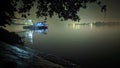 Boat standing on the river side attached by the stand with lights on in the night