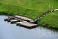 Boat station on the river and a green meadow, summer day, boats on the shore