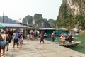 Boat stop with many tourists waiting for traveling inside limestone cave with limestone island in background in summer.