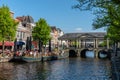 Boat terrace full of people enjoying the sun, food and drinks in the canal of the old town center of Leiden. Bridge