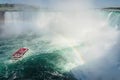 Boat with tourists sailing under the rainbow towards Niagara falls