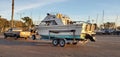 a boat on a trailer by the car is parked at the pier with a yacht Royalty Free Stock Photo