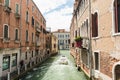 A boat traveling along a canal of Venice while two tourists taking a souvenir photos.
