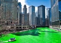 Boat travels across the Chicago River which is dyed green for St. Patrick`s day as crowds surround scene.