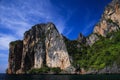 Boat trip along the coast line of tropical island Ko Phi Phi along impressive steep red rock wall rising high into blue sky Royalty Free Stock Photo