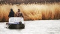 Boat with two men fishermen in the thickets of reeds on the river.