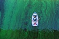 a boat with two sailors floats on green water