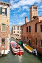 Boat under a bridge on a narrow canal sidelined by old buildings