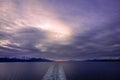 Boat wake, fiery sunset, snow capped mountains and calm seas