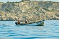 A boat in the water behind cliffs