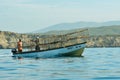 A boat in the water behind cliffs