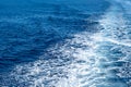 Boat white wake, on blue sea background, view from the ship. Mediterranean sea cruise Royalty Free Stock Photo