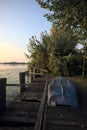 Boat on a wooden pier by the lakeshore next to reeds at sunset