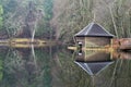 Boathouse and forest reflected in still waters of Loch Dunmore, Scottish Highlands