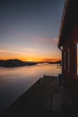 Boathouse illuminated by sunset, surrounded by tranquil waters and mountains in the backdrop. Royalty Free Stock Photo