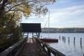 Boathouse with jetty and a sailing boat on the lake on a sunny day, copy space