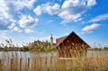 Boathouse with a thatched roof under a blue sky with white clouds and Schwerin Castle in the background