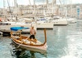 Boatman in cruise boat and many yachts in harbor close the islands Birgu with historical houses