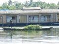 Boatman transporting fodder past a houseboat on backwaters, Keral, India