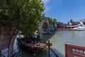 Boatman transports Chinese tourist gondola under Fangsheng bridge on canal