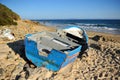 Abandoned small wooden boat -patera- on a beach near Tarifa, coast of Andalusia, Spain.