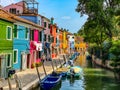 Boats and colorful traditional painted houses in a canal street houses of Burano island