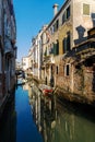 Boats covered from rain parked in the water next to the house in canal of Venice.