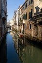 Boats covered from rain parked in the water next to the house in canal of Venice.