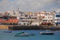 Boats docking at Corralejo marina port harbour with beach, concrete pier & white wash buildings at Fuerteventura, Spain